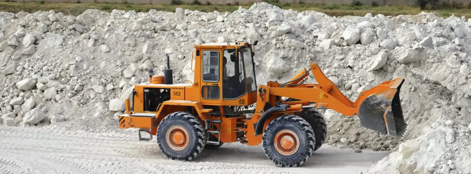 A wheel loader working a stockpile of white raw kaolin